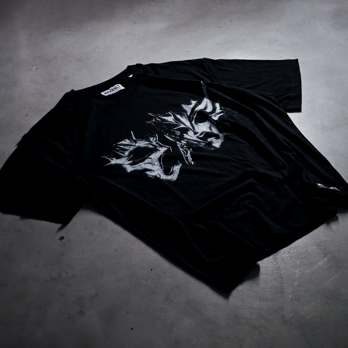 T-shirt NOXCULT Mascarade plié sur fond sombre